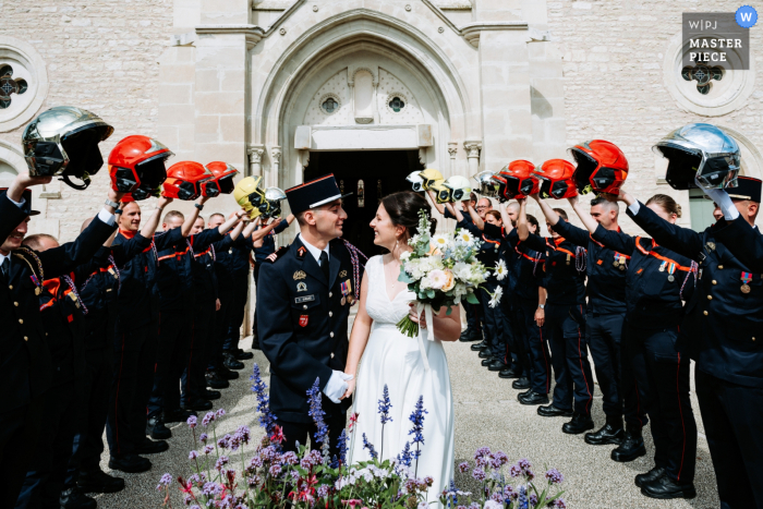 Poitiers Firemen Make Way for Newlyweds' Grand Wedding Exit Amidst a tunnel of held helmets, the newlyweds make their grand exit from the church in Poitiers, Vienne, with the help of local firefighters.