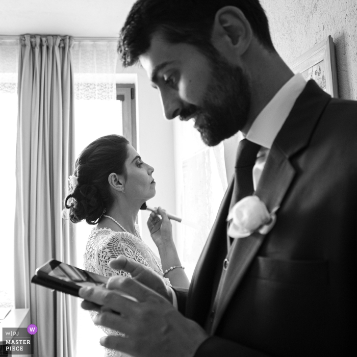 Brittany Wedding: Bride Prepares While Groom Gets Family Help on Phone Captured in Brittany's Ille-et-Vilaine region, the documentary image shows the bride putting on finishing touches while the groom coordinates with family before their marriage ceremony.