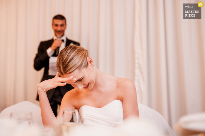 Blushing Bride: A Humorous Wedding Speech Moment in Buckinghamshire, UK Despite being the center of attention, the bride couldn't help but blush and hide her face during her groom's embarassing wedding speech in Buckinghamshire, UK.