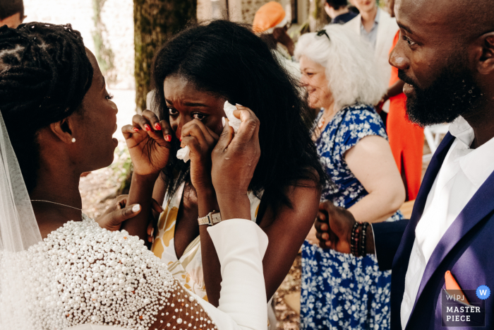 Joyful Wedding Moment: Friend Comforted by Bride at Domaine Laplaud The bride provides comfort to her friend, while her brother looks on, in this heartwarming moment captured by a WPJA wedding photographer at Domaine Laplaud.