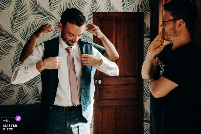 Getting Ready for the Big Day: A Groom's Journey at Château de la Rose Groom getting ready with the help of his groomsmen at the Château de la Rose captured by a talented WPJA wedding photographer.