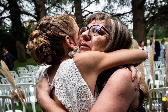 Genuine love radiates in the embrace between bride and mother, captured by a skilled WPJA wedding photographer at the picturesque Chateau de Loubejac in Montauban, France.