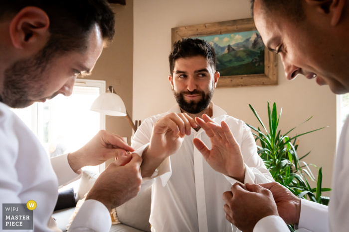 Captured by a WPJA wedding photographer, this moment at the groom's house in Pau, France captures the camaraderie as his friends assist in putting on his cufflinks.