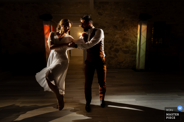 The newlyweds sway gracefully, surrounded by dramatic lighting, at their ball opening in the Bastide de Jaillans, a stunning location in the French countryside.