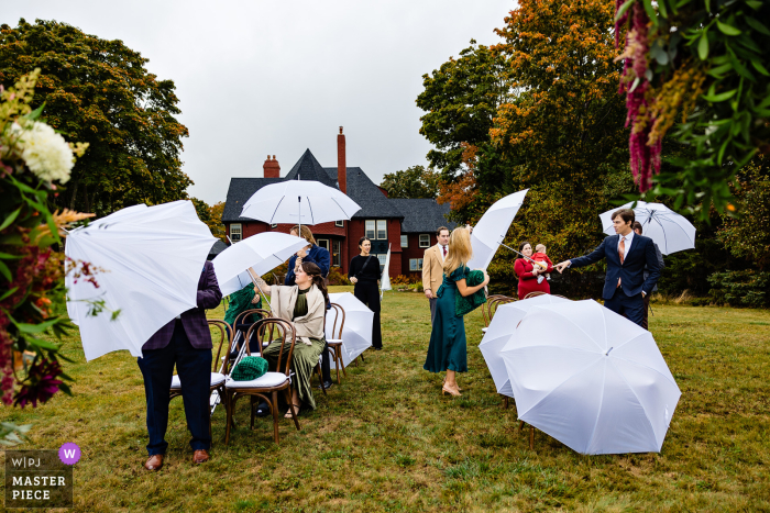 Guests Gather with Umbrellas for Outdoor Bar Harbor Wedding in the Rain Amidst the rain, the wedding guests prepare under white umbrellas, creating a picture of anticipation and togetherness at this Bar Harbor, Maine ceremony.