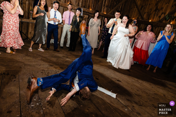 A joyful celebration at Broadturn Farm in Scarborough, Maine, captured by a talented WPJA wedding photojournalist, showcasing the groom's playful spirit as he somersaults during the lively reception.