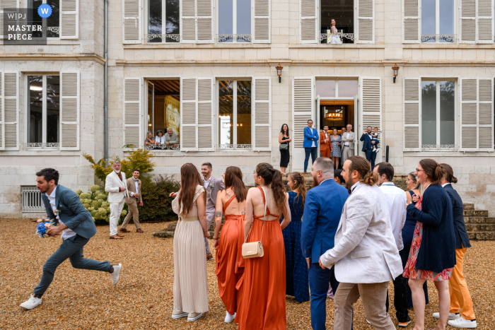 Amidst the joy and laughter, a lucky guest sneaks away with the bride's bouquet during the lively reception at Centre-Val de Loire wedding venue captured by a talented WPJA photojournalist.