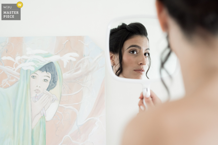 Bride Admires Makeup in Mirror as Painting Observes Scene at Domaine de Villary, Nîmes At Domaine de Villary in Nîmes, the bride admires her makeup in the mirror, while a painting on the wall seems to watch over the scene, adding an artistic touch to the moment.