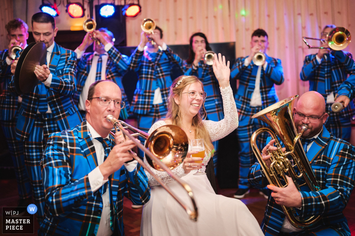 Bride Joyfully Stands Among Brass Band, Radiating Happiness Amid Lively Music and Energy The bride stands joyfully in the middle of the brass band, enveloped by lively music and energy, her smile radiant as she shares this unique moment with the musicians.