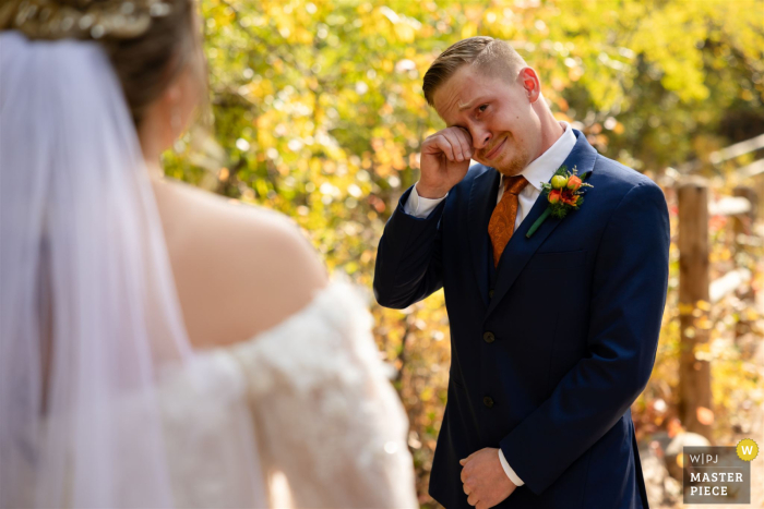 In the breathtaking scenery of North Cheyenne Canyon Park, Colorado Springs, CO, the groom is visibly moved, his emotions overflowing upon seeing his bride for the first time, creating a touching and unforgettable moment.