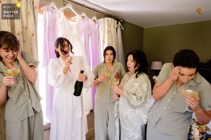 Champagne Cork Pops and Surprises Bride and Bridesmaids at BrookLodge, Ireland At BrookLodge, Ireland, a champagne cork unexpectedly pops, narrowly missing a bridesmaid, leading to surprised expressions from the bride and her bridesmaids.