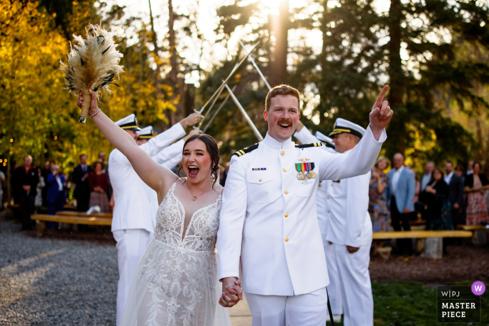 At Blackstone Rivers Ranch, the bride and groom jubilantly celebrate after passing through a dramatic tunnel of swords, their smiles radiating excitement and joy as guests cheer them on.