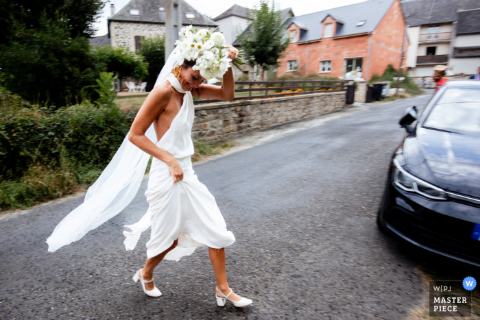 Bride Gracefully Escapes Rain to Preserve Wedding Attire in Streets of Île-de-France Amidst the streets of Île-de-France, the bride hurries, gracefully attempting to escape the rain while preserving her elegant wedding attire.