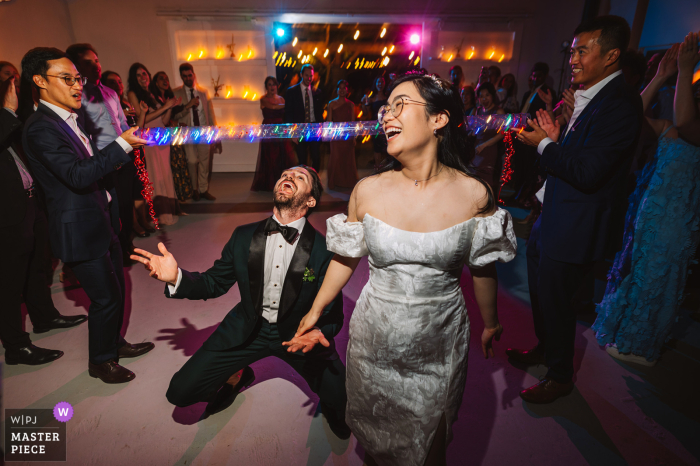 Bride and Groom, Both Lawyers, Share a Laugh by the Bar at M&D Farm, Westerlo, NY At M&D Farm, Westerlo, NY, the groom and bride, both accomplished lawyers, share a laugh pssing by the bar, creating a playful nod to their shared profession.