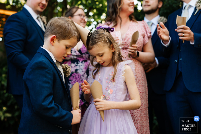 At the picturesque Triton Inn, Yorkshire, two delighted young guests clutch confetti cones, their eyes filled with excitement for the wedding festivities yet to come.