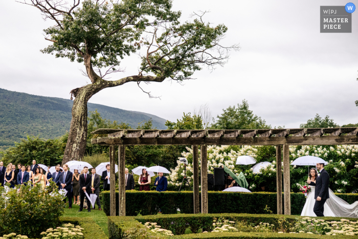 Bride Embraces Rain as She Walks Toward Her Beloved at Hildene in Manchester, VT Amidst the peaceful outdoor backdrop of Hildene in Manchester, VT, the bride gracefully makes her way towards her beloved, embracing the rain on her special day.