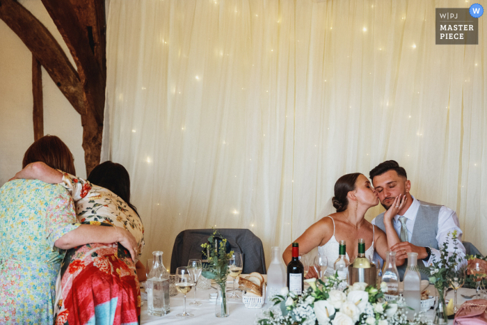 Experience the tender exchange shared between a husband and wife at the wedding table in Henley on Thames, UK, beautifully captured by a documentary wedding photographer.