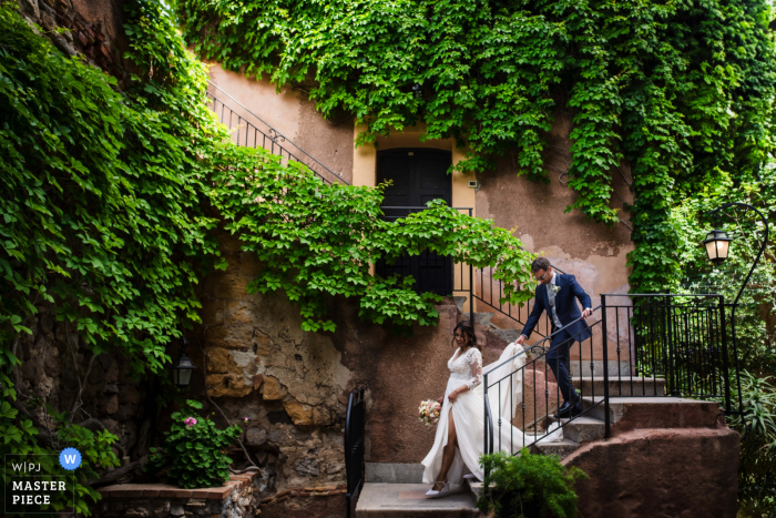 Bride and Groom Descend Castle Stairs at Castello San Nicola in Trabia Captured by Wedding Photojournalist A beautiful moment as the bride gracefully descends the castle stairs with her groom, on their way to their reception at Castello San Nicola in Trabia - a stunning scene captured by a talented wedding photojournalist.