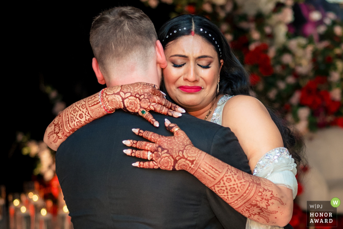 At a Los Angeles reception venue, the bride and groom share their first dance together. The bride wraps her arms around him, her eyes closed and expression full of emotion, making the moment deeply touching and memorable.