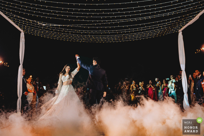 At an outdoor ceremony in the UAE, the couple shares their first dance, with a smoke machine creating an effect that makes it look like they are gracefully dancing on a cloud.