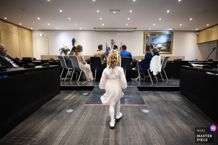 Young Girl Marches Toward Mother at La Ciotat City Hall, Captured in Heartfelt, Candid Moment At City Hall in La Ciotat, France, a little girl marches purposefully toward her mother, who is not the bride, captured in a shot from behind at the back of the room.
