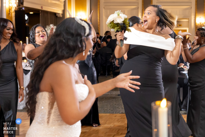 At a Baltimore, Maryland reception, a woman beams with surprise and joy after catching the bouquet. Her delighted expression captures a wedding tradition.