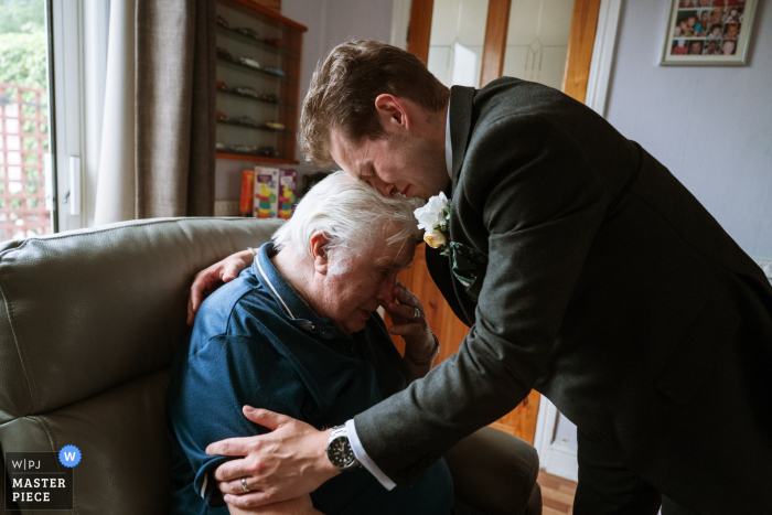An emotional groom embraces his ailing grandfather at a wedding in Wednesbury, UK, capturing a heartfelt and tender moment.