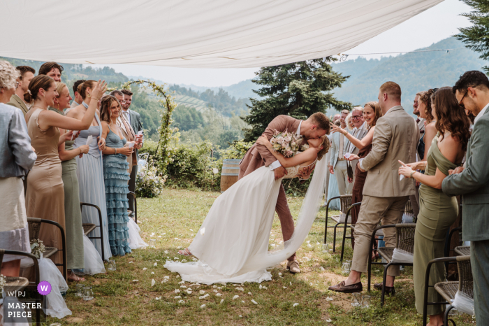 At the I Muri venue in Langhe, Piedmont, a newly married couple shares a kiss and a dip under a tent after their ceremony on the grass. The award-winning photo highlights the photographer’s skill at documenting romantic moments.