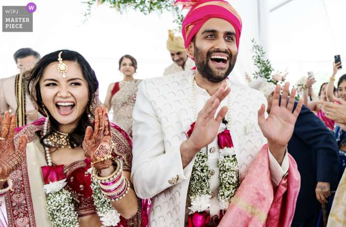 At Greystone at Piedmont Park in Atlanta, a dancing couple exits their Hindu wedding ceremony with hands in the air, beaming with huge smiles. The photo captures the pure joy and celebration of the occasion.