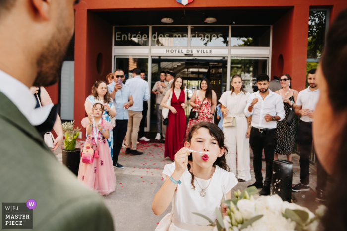 Bubble-filled wedding exit at the city hall of Saint-Priest, France with the happy couple and their bridesmaid.