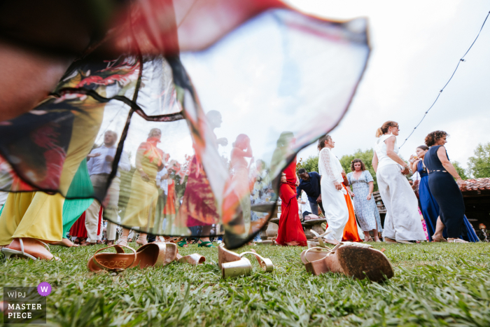 In Inharria, Saint-Pée-sur-Nivelle, guests dance barefoot on the grass, twirling their dresses with joyful abandon. A low-angle shot from ground level captures the playful movement and carefree spirit under flowing skirts.