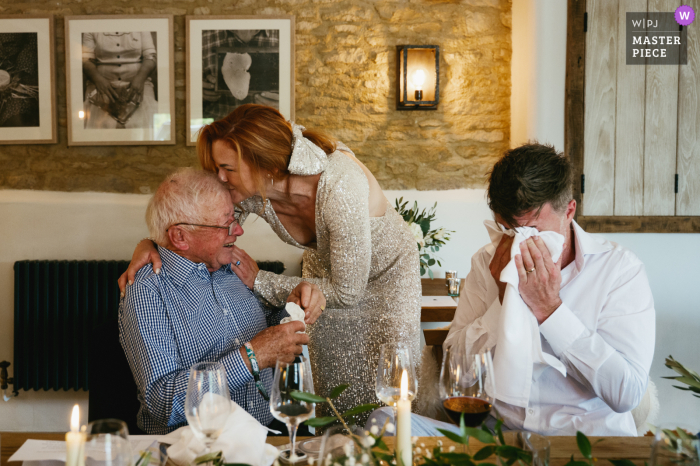 Tears And Laughter At The Bell In Charlbury, Cotswolds, England, As Family Shares Speeches And The Bride Kisses Her Father-In-Law. During speeches at The Bell in Charlbury, Cotswolds, England, both the groom and his father are moved to tears, while the bride kisses her father-in-law and laughter follows.
