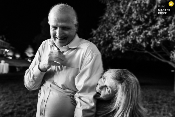 Late-Night Reception In Monkton, Maryland, Includes Laughter As A Playful Wife Bites Her Husband, Surprising Wedding Guests. During a late-night reception at a private residence in Monkton, Maryland, a wife playfully bites her husband, bringing laughter and spontaneity to the evening’s celebrations.