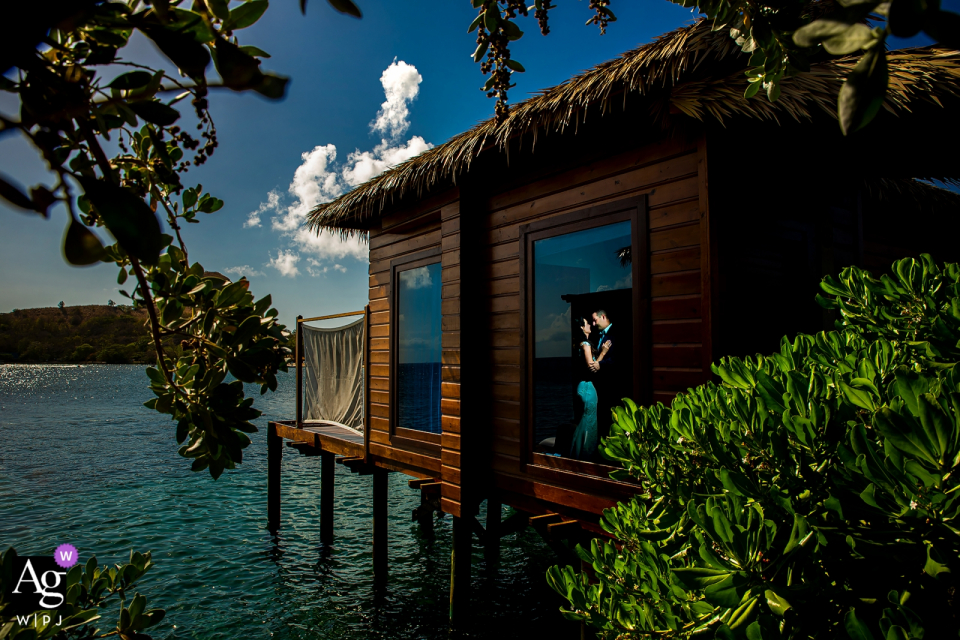 De bruid en bruidegom poseerden voor een portret in Sandals Grande St. Lucian in een bungalow boven het water