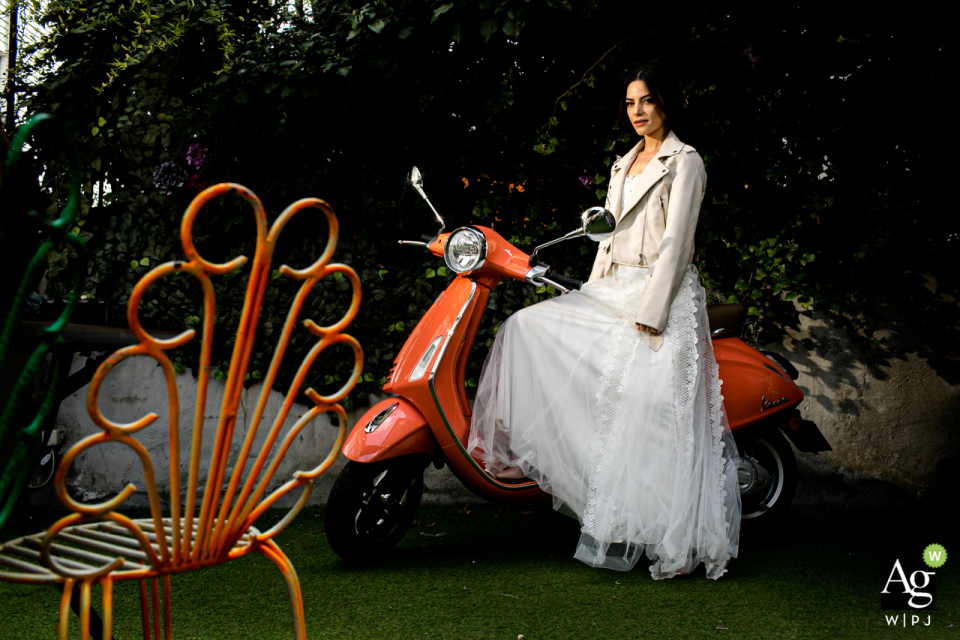 Grand Ankara Hotel wedding venue photography | Bride is sitting on a Vespa which is next to wall and looking at the camera next to a chair Grand Ankara Hotel wedding venue photography | Bride is sitting on a Vespa which is next to wall and looking at the camera