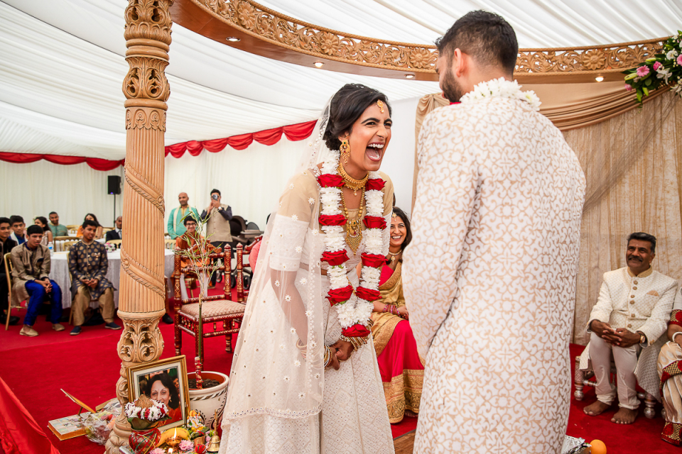 Gli sposi si divertono facendo il nodo al Bhaktivedanta Manor, Aldenham, Hertfordshire Fotografia di cerimonia di matrimonio indù da un evento sotto una tenda