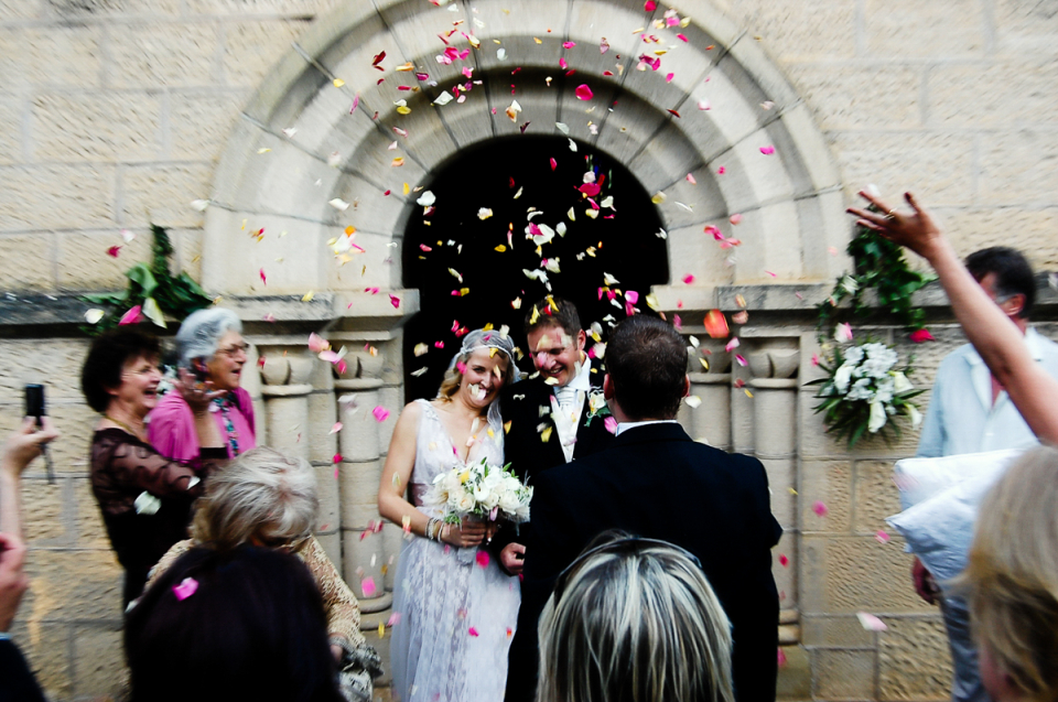 By Grace Alone, South Africa wedding ceremony photography showing the bride and groom under flower petals By Grace Alone, South Africa wedding photography showing the bride and groom exiting under a shower of flower petals