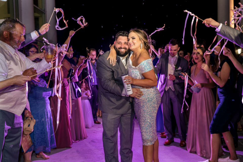 A Jefferson Parish wedding venue picture of the couple hugging at the end of their Jean Lafitte reception in Louisiana A bride and groom embrace while surrounded by friends at their Jean Lafitte wedding reception party in Bayou Barataria, Louisiana