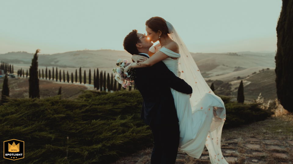 A couple poses for a romantic session at Agriturismo Baccoleno in Tuscany. He lifts her as the low sun creates a warm glow, capturing a joyful and intimate scene.