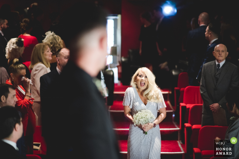 Photo by: <a href="https://www.wpja.com/contests/2018-v02-photography-competition/2180721">Nick Brightman - Wolverhampton West Midlands</a> Electric Cinema, Birmingham wedding ceremony photography - the bride expresses joy as she enters the ceremony