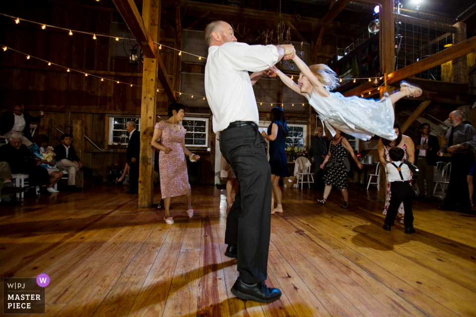 Lo sposo oscilla intorno alla bambina sulla pista da ballo al The Barn at Harvest Moon Pond, Poynette,