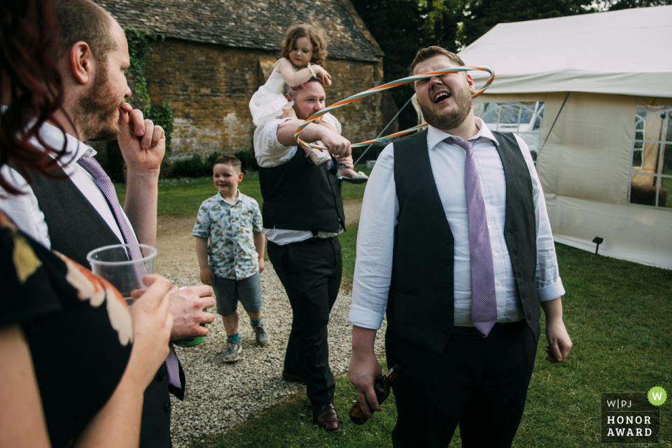 guests playing with children and hula hoops Stanway House, Cheltenham outdoor wedding reception - photographer captured guests playing with children and hula hoops