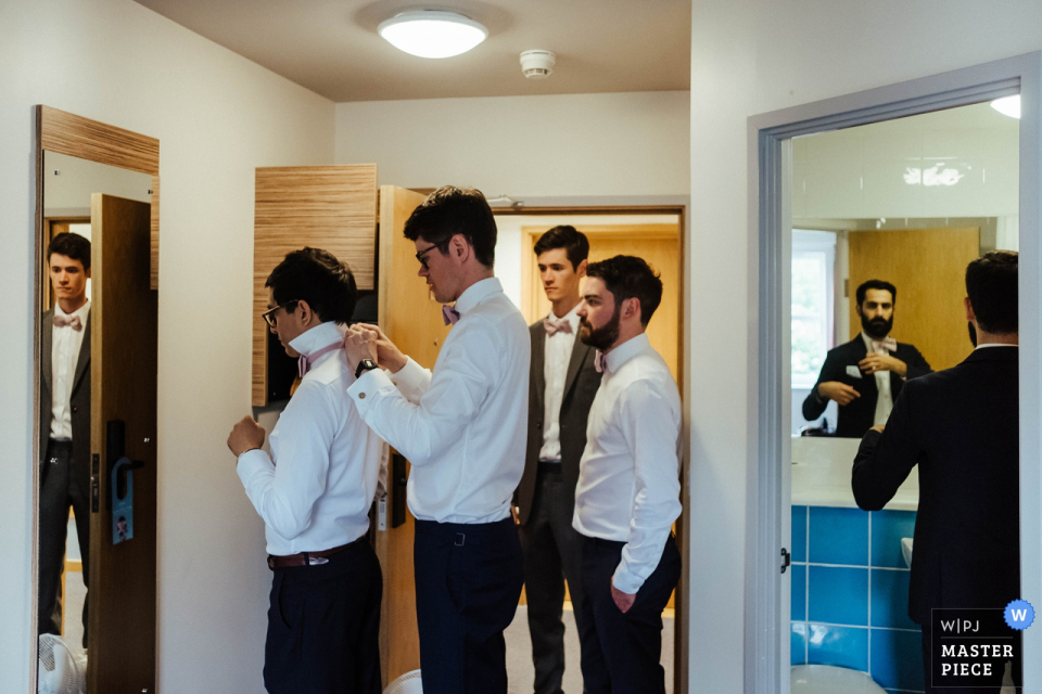 Groomsmen die elkaar helpen zich klaar te maken voor de huwelijksceremonie in de Barnston Lodge