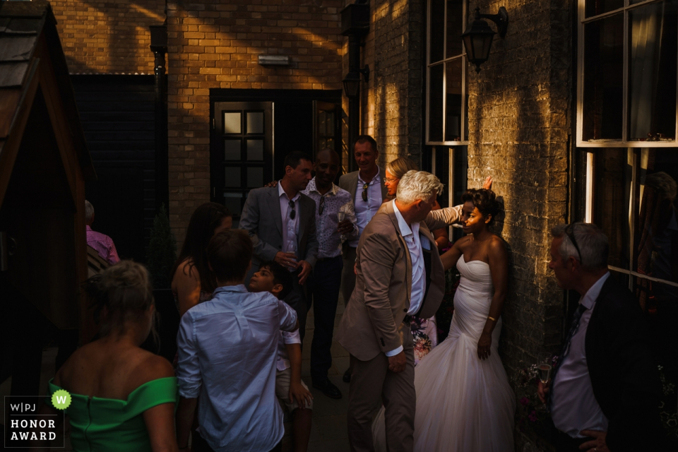 The bride, groom, and guests mingle in the sunny courtyard The bride, groom, and guests mingle in the sunny courtyard at the Hotel Du Vin, Cambridge, UK wedding reception