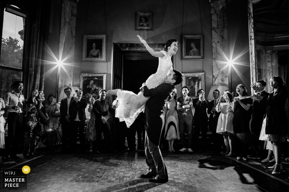 Groom lifts up the bride while dancing at the reception dance party Groom lifts up the bride while dancing at the wedding reception at the Sudeley Castle, United Kingdom