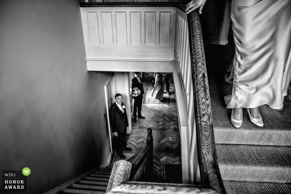 Great Tythe Barn en Tetbury - Fotografía de boda de la novia a punto de bajar las escaleras - Padre de la novia