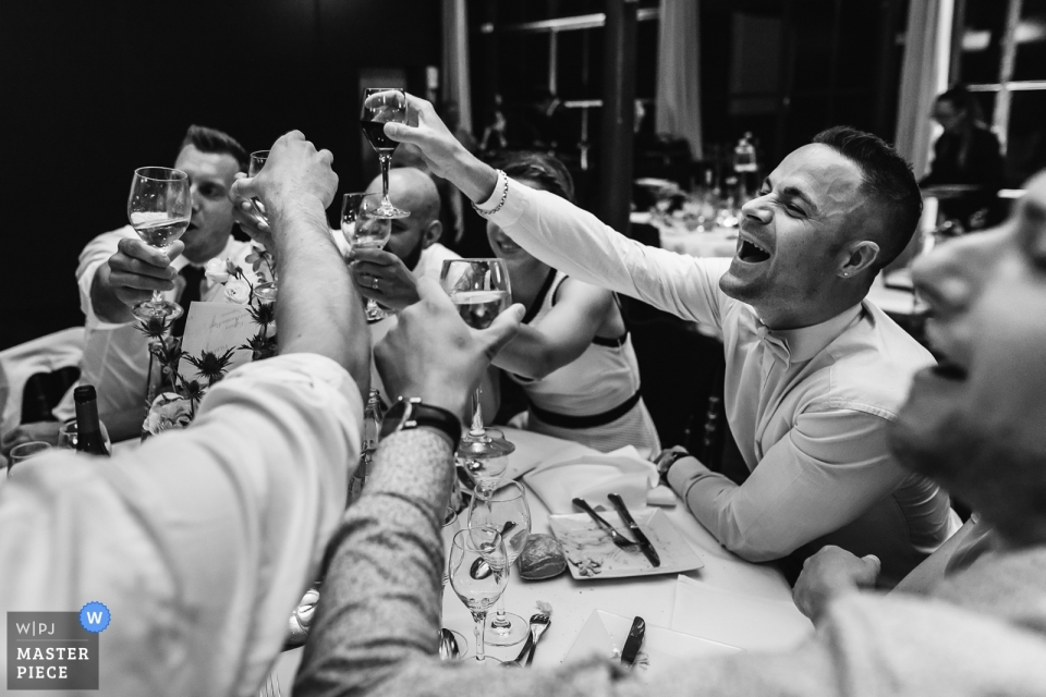 Fotografía documental de la boda del Chateau de la Cour Senlisse de los invitados de la recepción brindando copas en su mesa