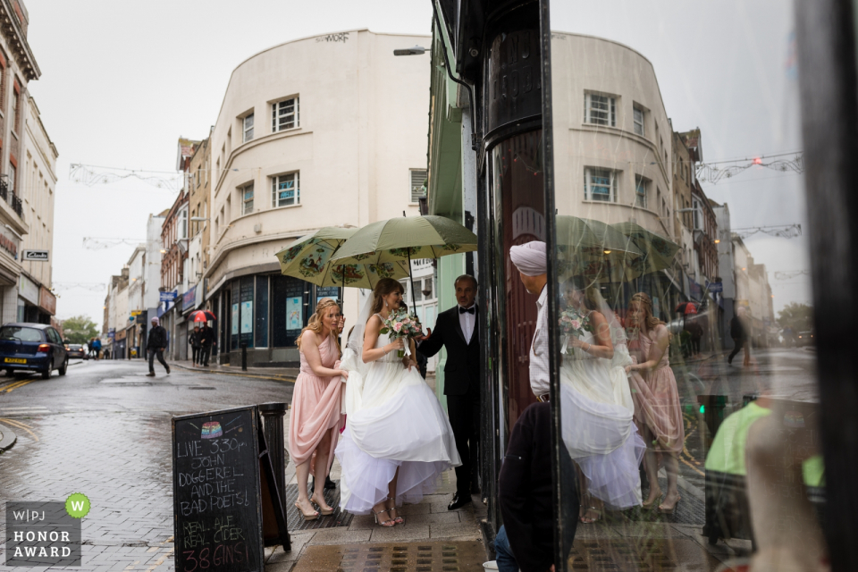 Foto: <a href="https://www.wpja.com/contests/2018-v16-Fotografie-wettbewerb/best-wedding-photographers/2322446"> Catherine Hill - Canterbury Kent </a> Sands Hotel, Margate Kent - Hochzeit Foto der Braut, die das Gebäude aus dem Regen heraus betritt
