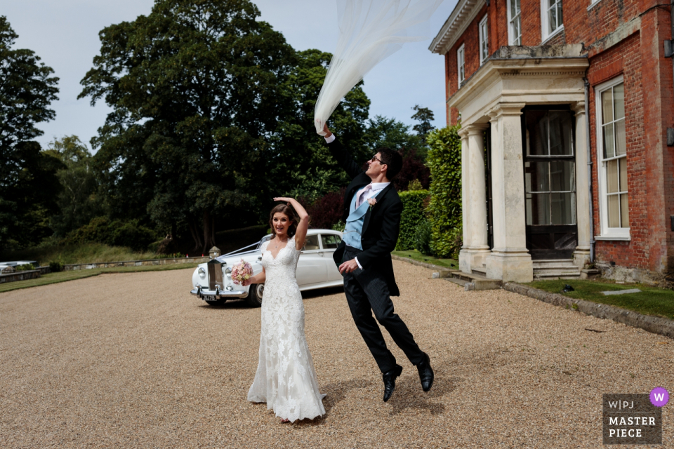 Foto: <a href="https://www.wpja.com/contests/2018-v16-Fotografie-wettbewerb/best-wedding-photographers/2322471"> Catherine Hill - Canterbury Kent </a> Der eigensinnige Schleier der Braut wird von ihrem schnell handelnden Ehemann am Squerryes Court abgerufen - Foto von einem Top-Hochzeitsreportage-Fotografen aus Kent