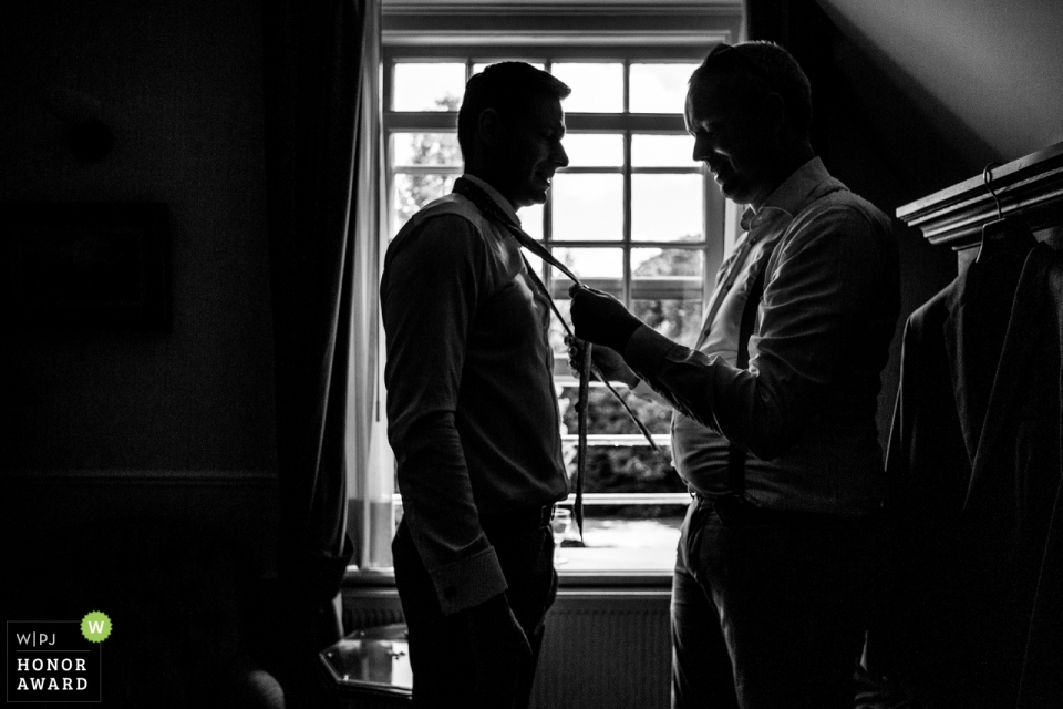 Kasteel De Wittenburg, Wassenaar, Netherlands wedding image of the Best man putting on tie with groom 